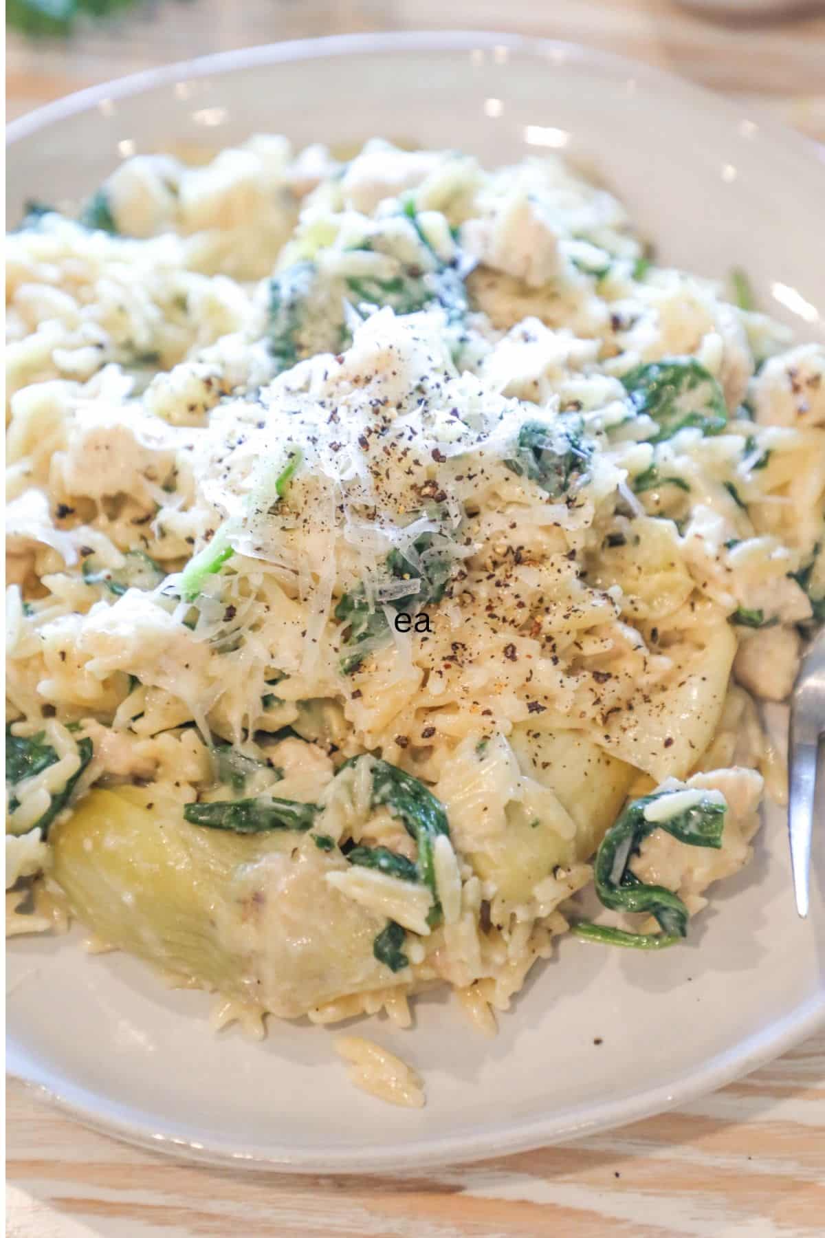 plate with a serving of spinach artichoke chicken orzo