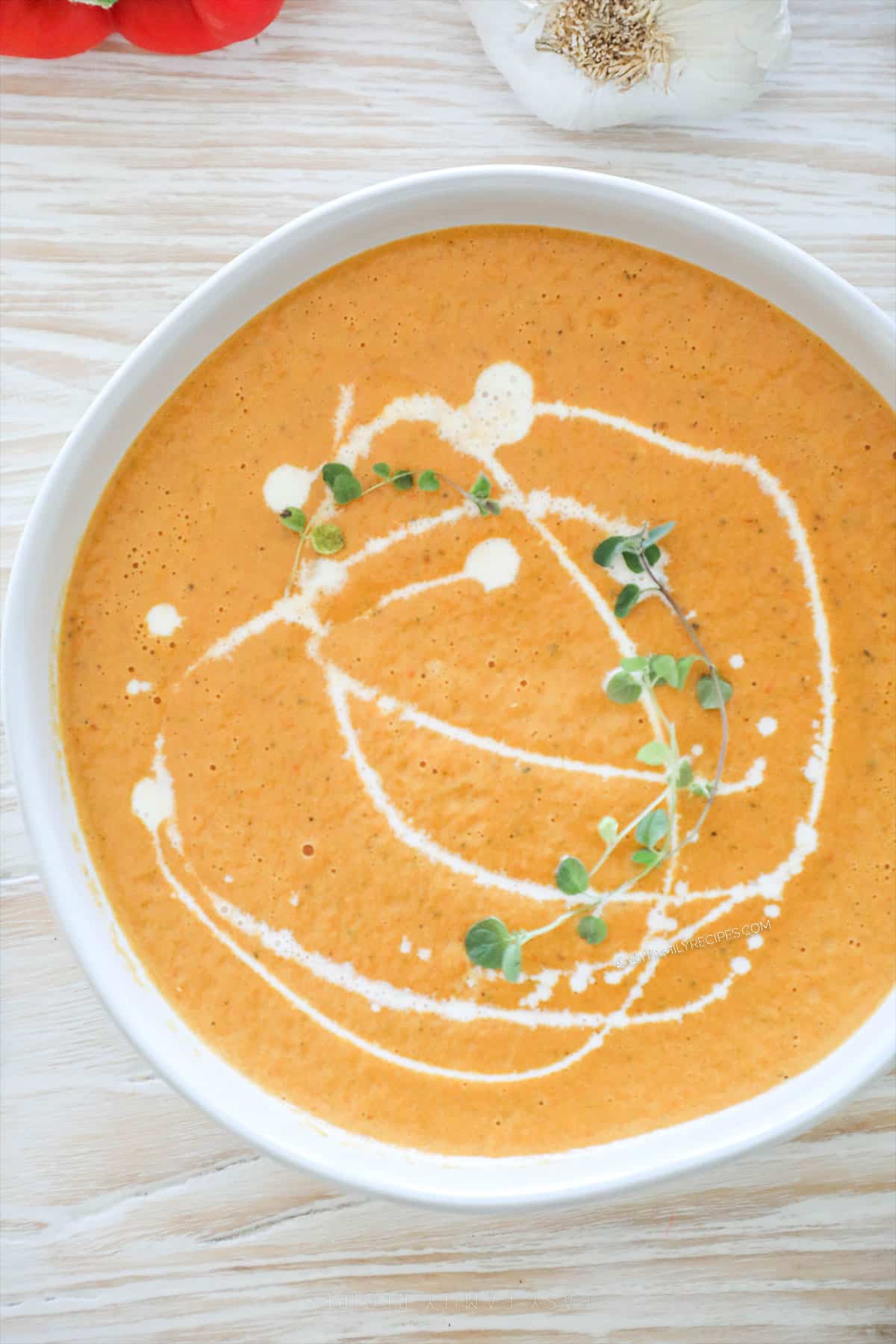 Top view of roasted veggie soup in a white bowl on a distressed wood background