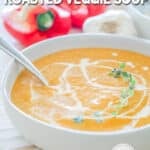 Bowl of roasted veggie soup. Roasted veggie soup in a white bowl with a spoon. Red bell peppers are in the background.