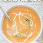 Top view of roasted veggie soup in a white bowl on a distressed wood background. The text reads, “Sheet Pan Roasted Veggie Soup”
