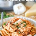 A bowl of Crockpot Sun Dried Tomato Chicken Alfredo with a silver fork. The text reads, “Crockpot Sun Dried Tomato Chicken Alfredo”