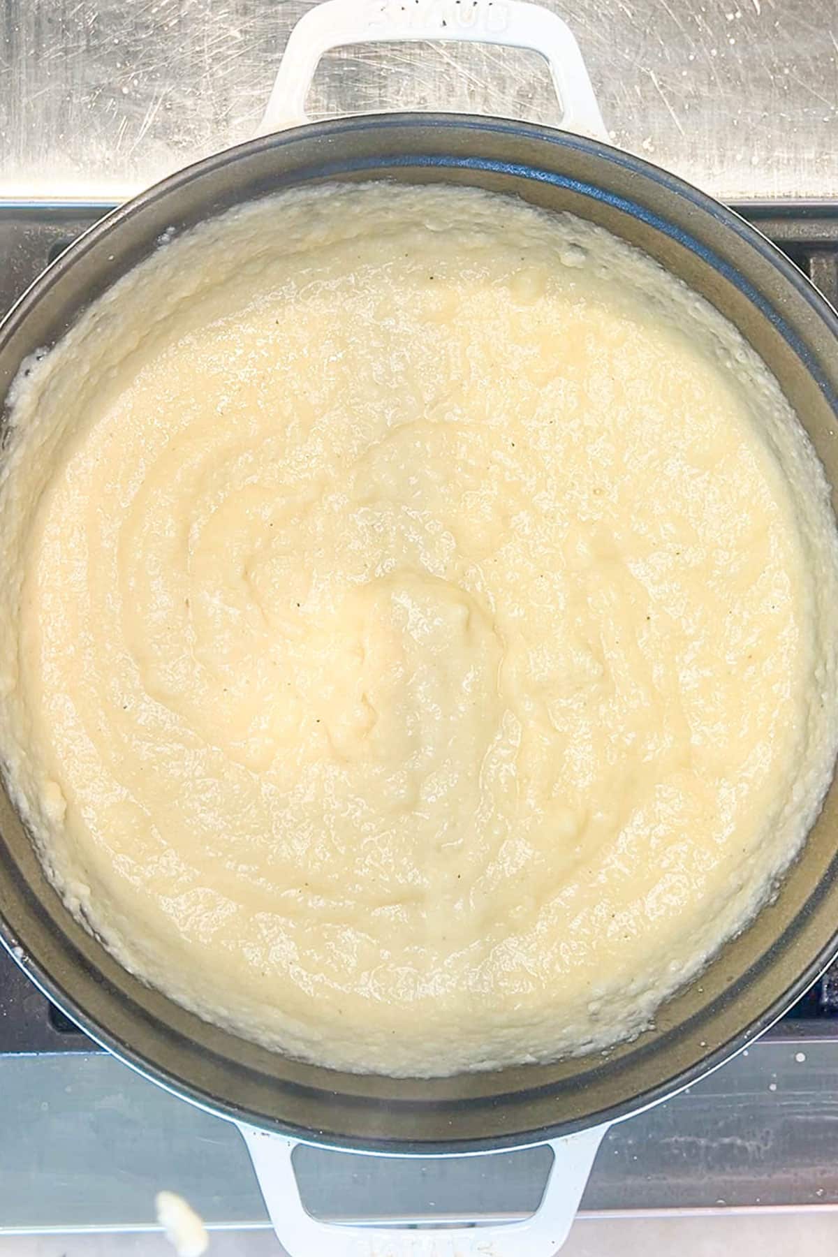 Cheese and butter melted into the cauliflower mixture in a pot.
