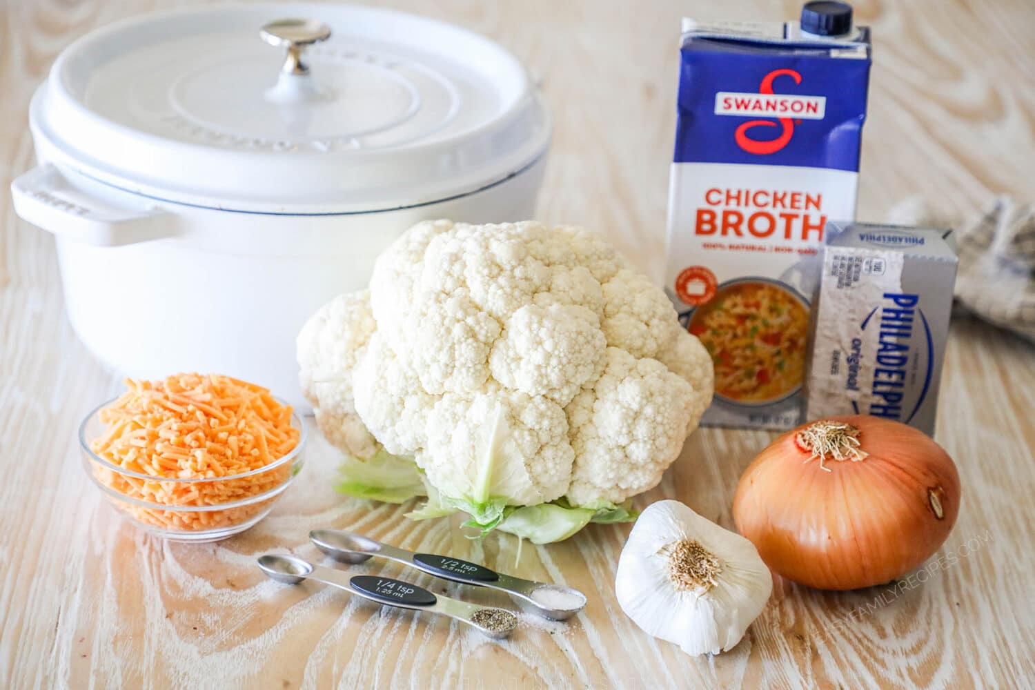 Ingredients needed to make loaded cauliflower soup on a wooden background.