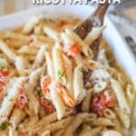 pasta being scooped out of pan using a wooden spoon.