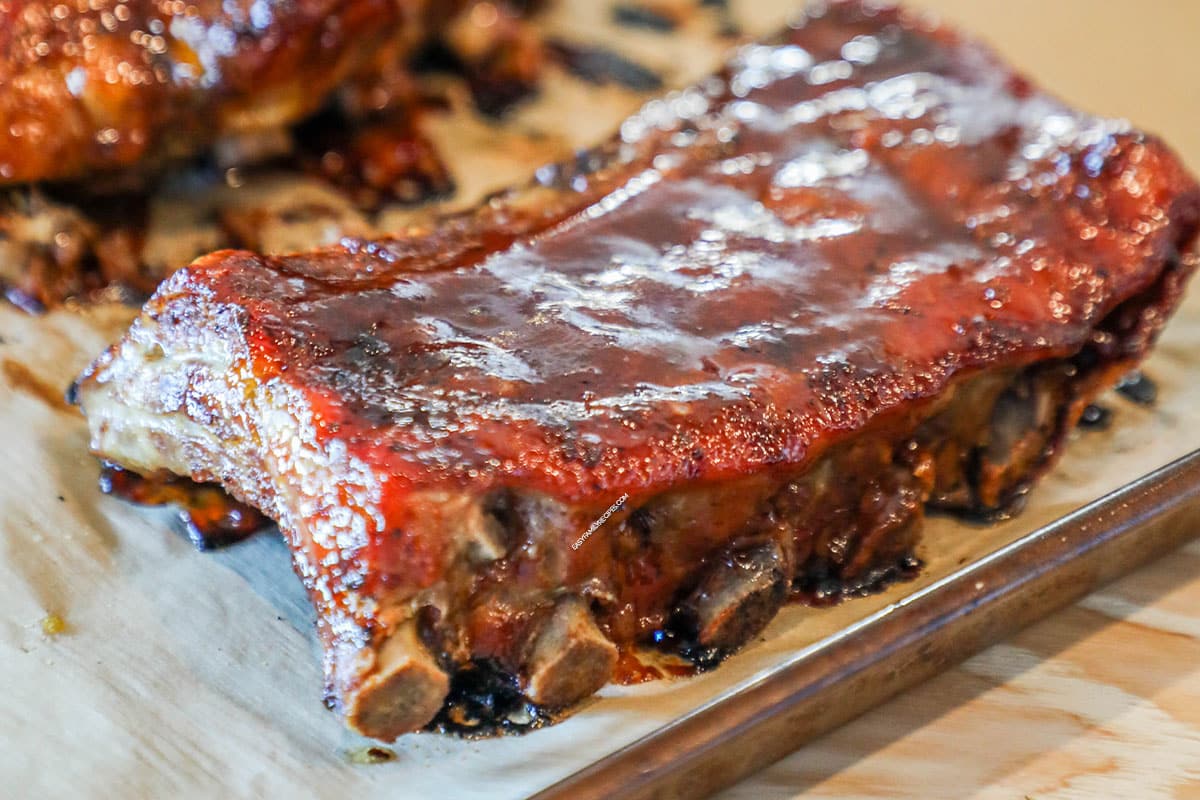closeup of a cooked honey bbq rib on a cutting board.