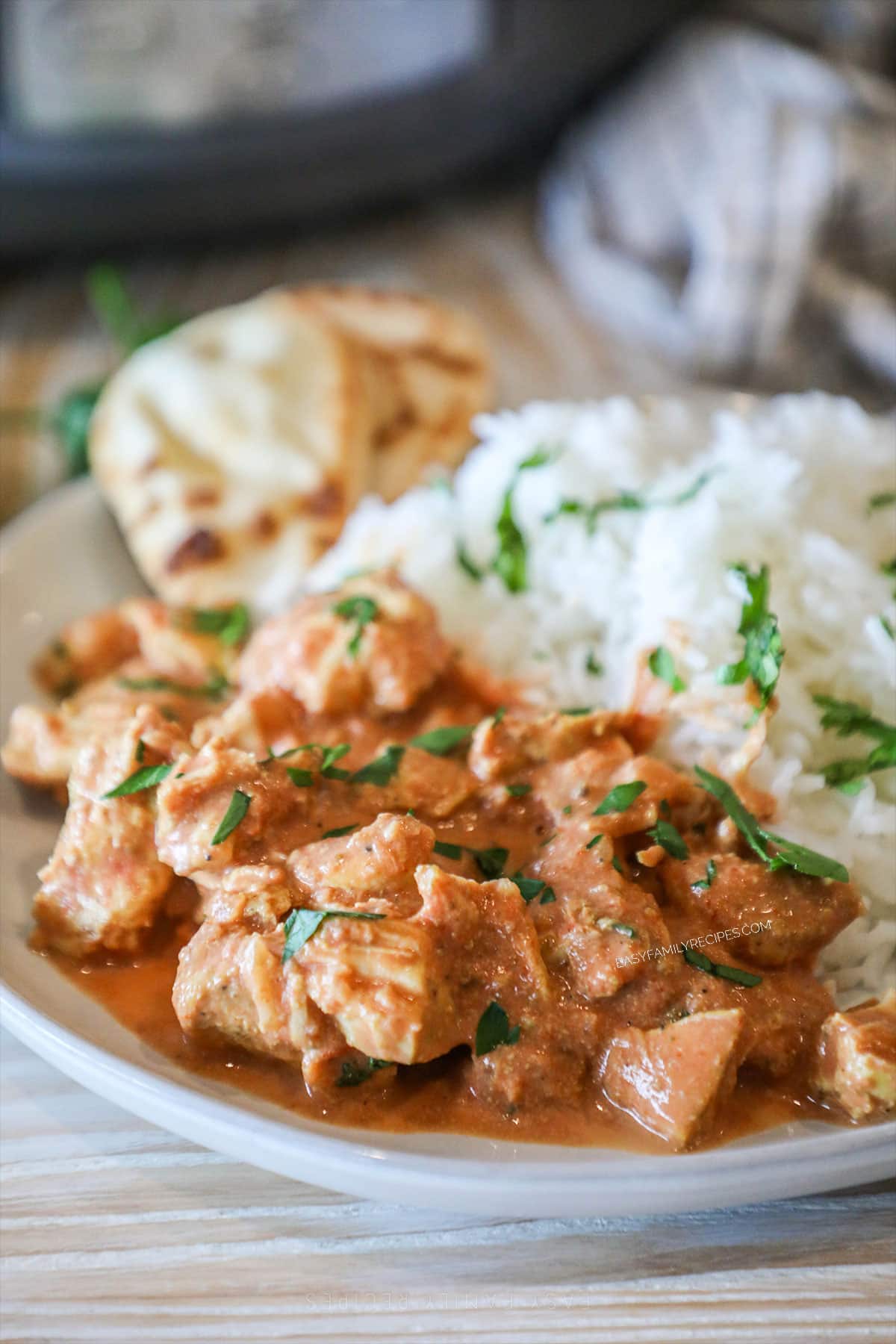 Slow cooker chicken tikka masala served on a plate with rice and naan, garnished with cilantro.