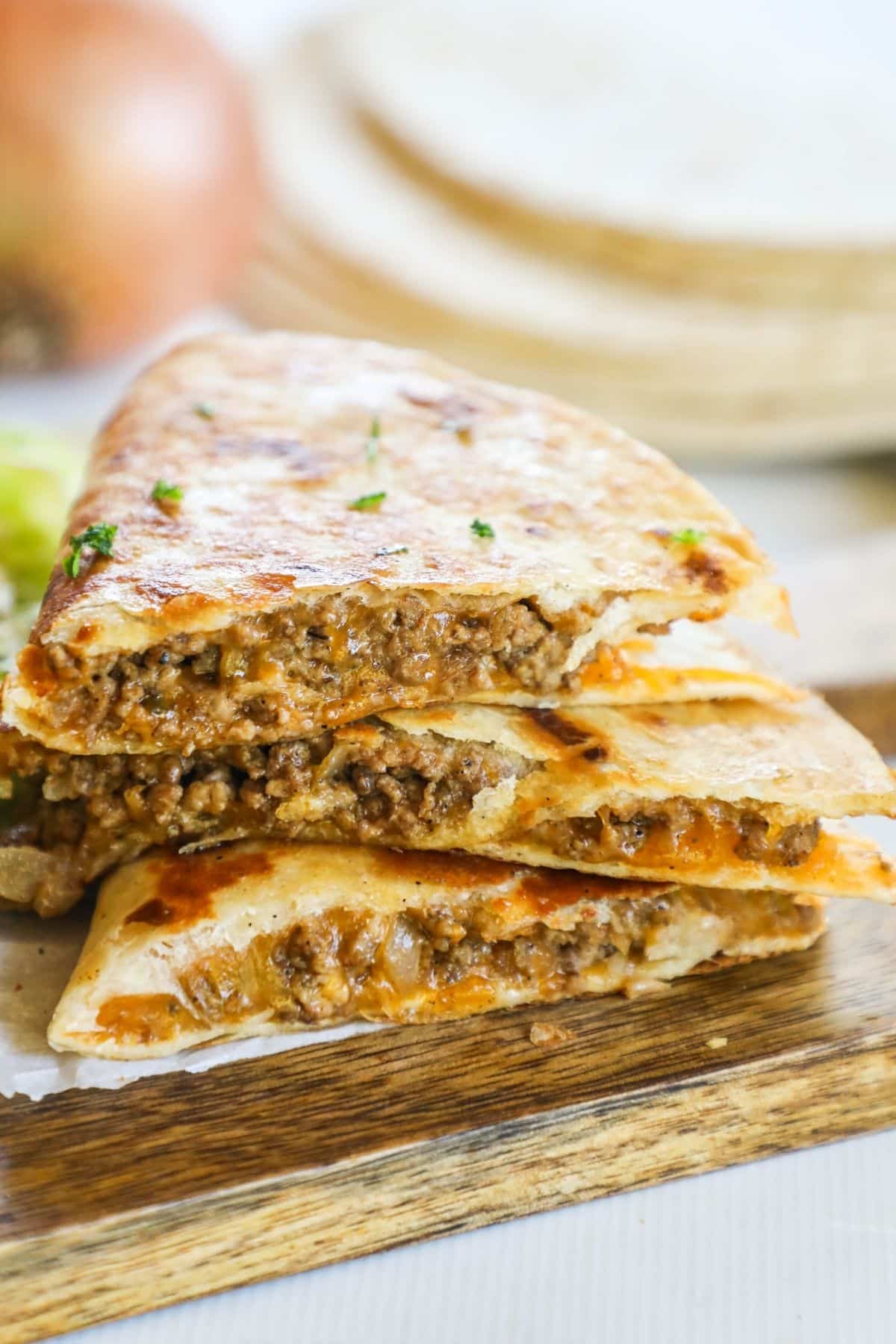 ground beef quesadillas stacked on a cutting board