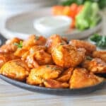 Boneless chicken wings coated in a honey BBQ sauce served on a cast iron serving platter.