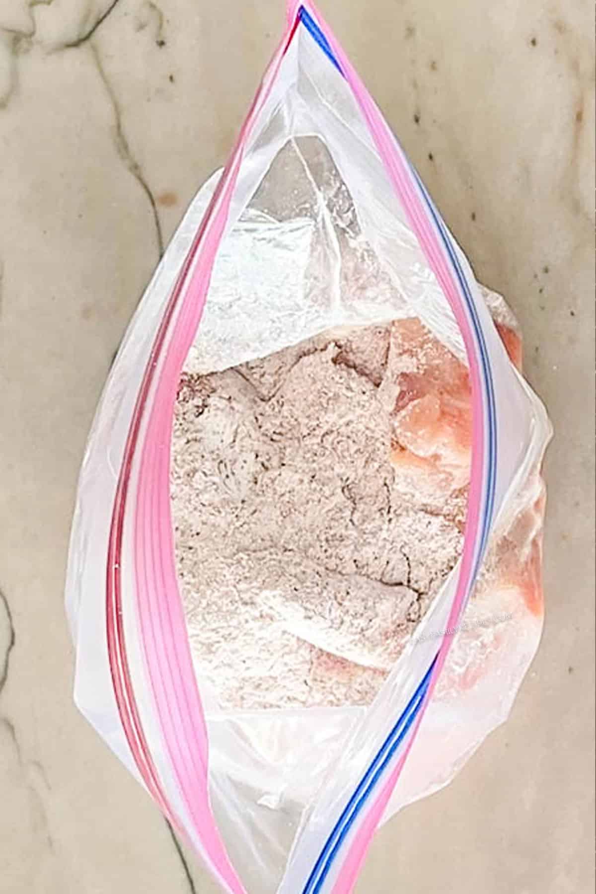 Pieces of chicken in a bag with spices, flour and cornstarch.