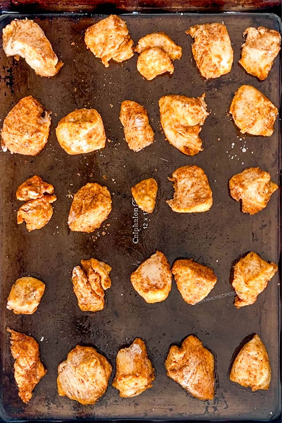 Baked crispy pieces of chicken on a sheet pan.