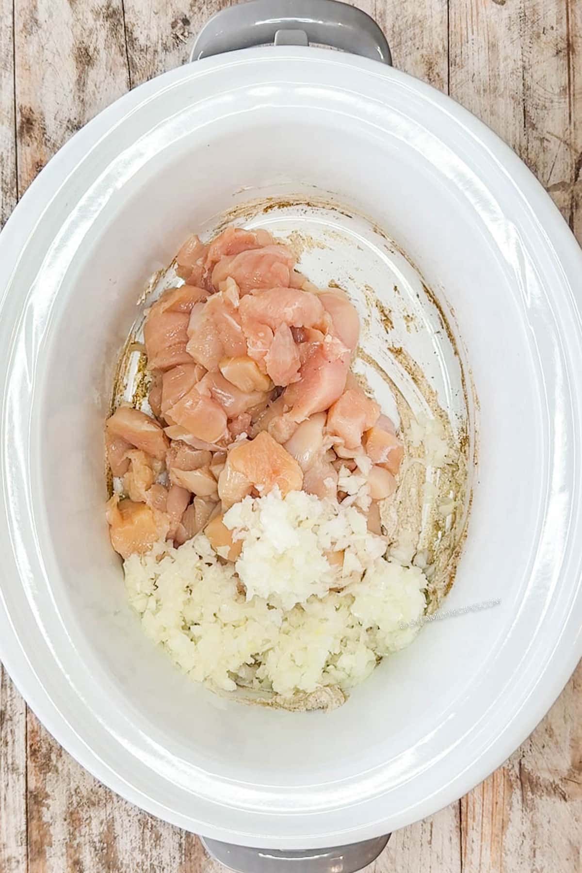 Diced chicken and onion added to the crockpot with the spices.