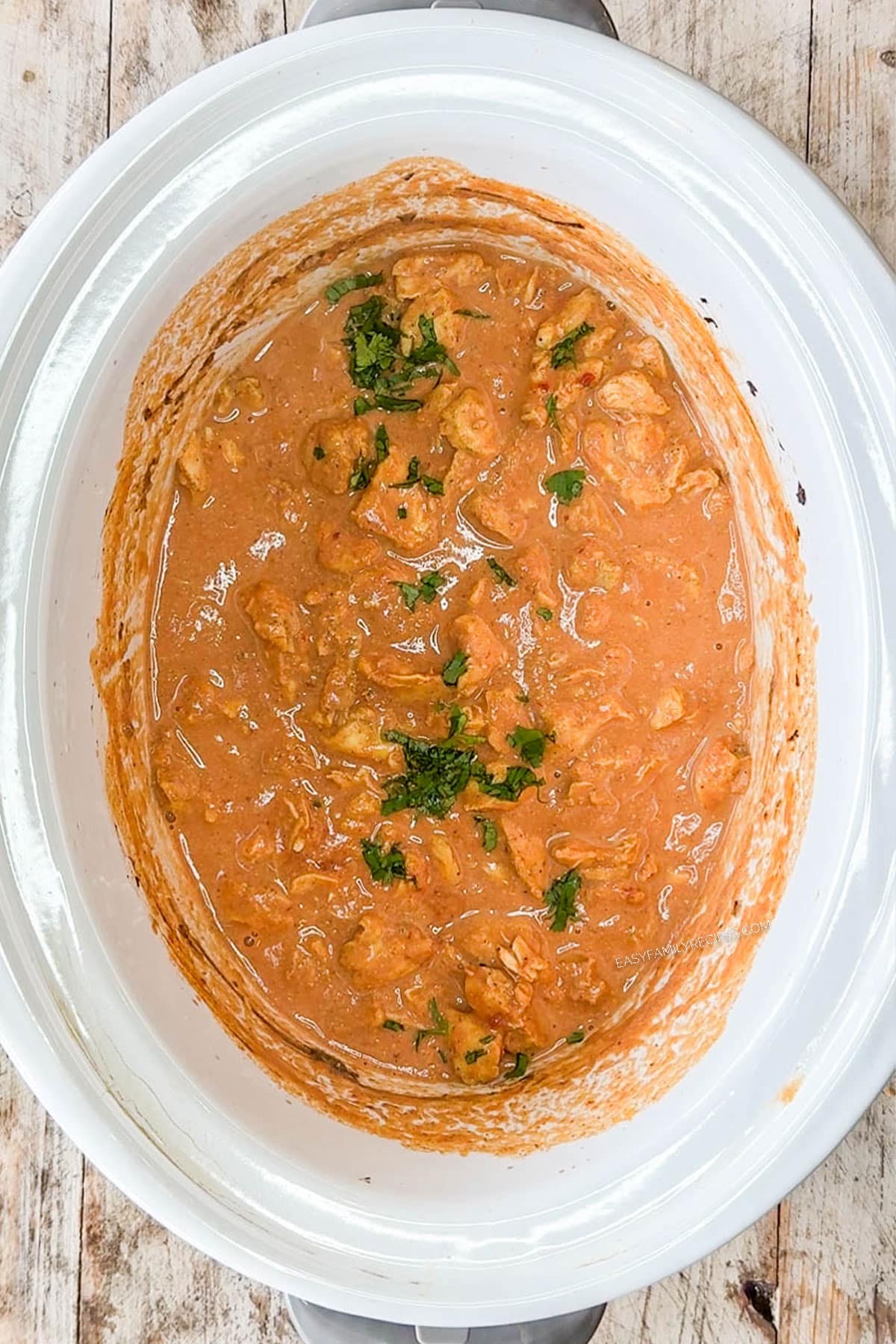 Slow cooker chicken tikka masala topped with cilantro in the crockpot.