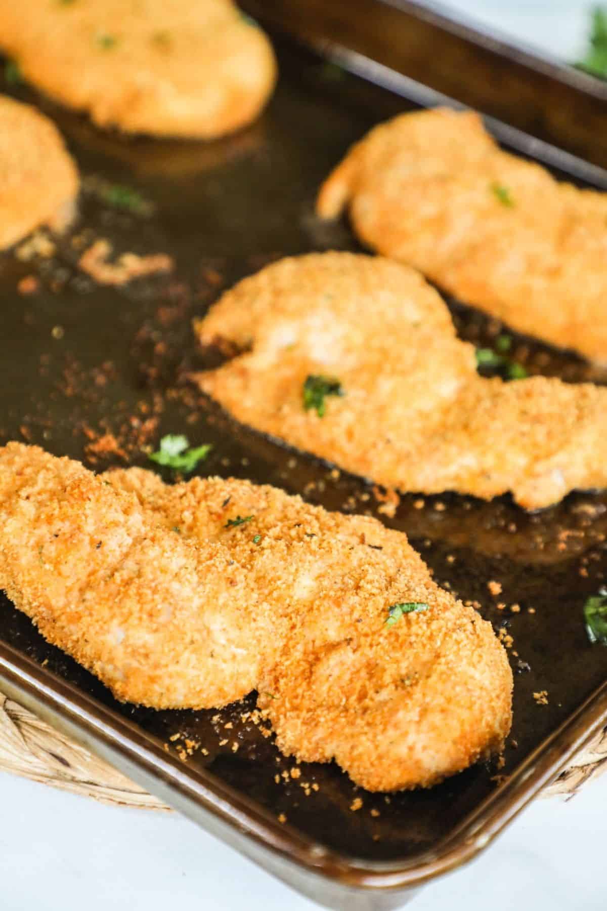 homemade shake and bake style chicken breasts on a baking sheet