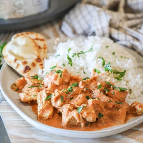 Place of chicken tikka masala with rice and naan on the side.