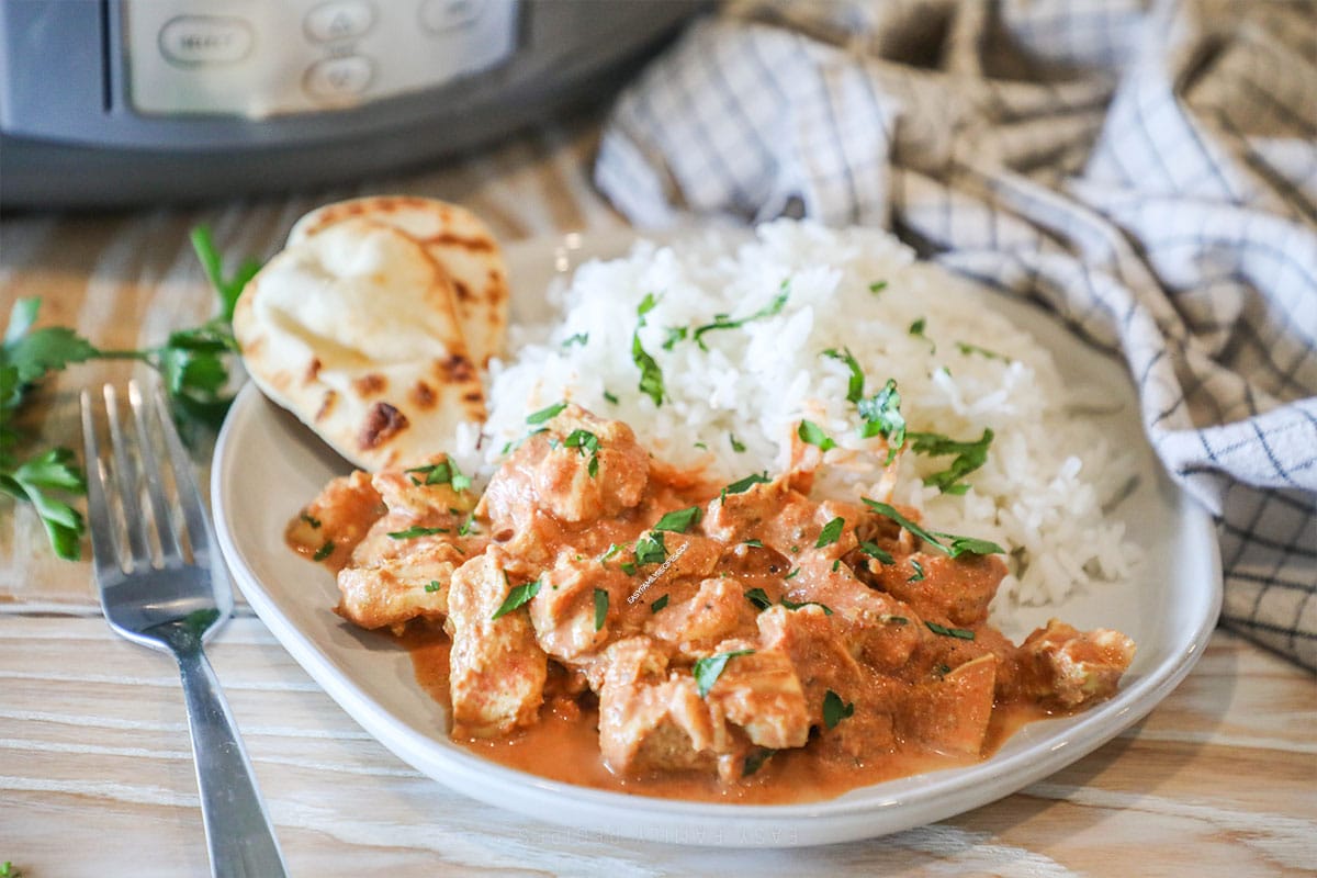 Place of chicken tikka masala with rice and naan on the side.