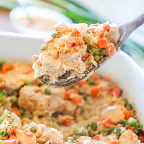 Bang bang chicken and rice bake on a wooden spoon.