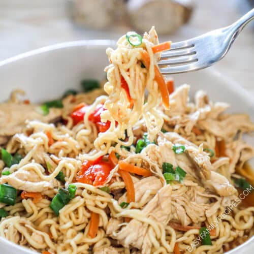A fork lifts a bite of ramen out of the bowl