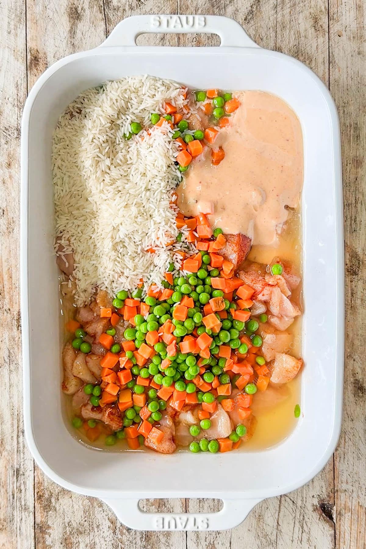 Rice, veggies, chicken broth and bang bang sauce added to the baking dish.