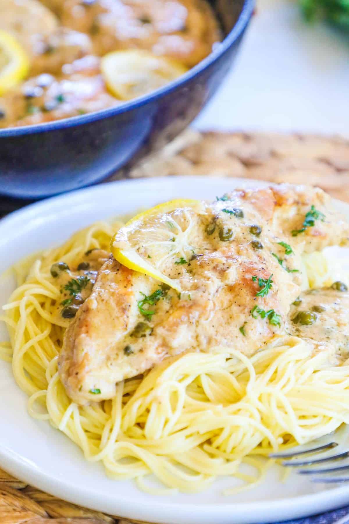 chicken piccata over pasta on a plate