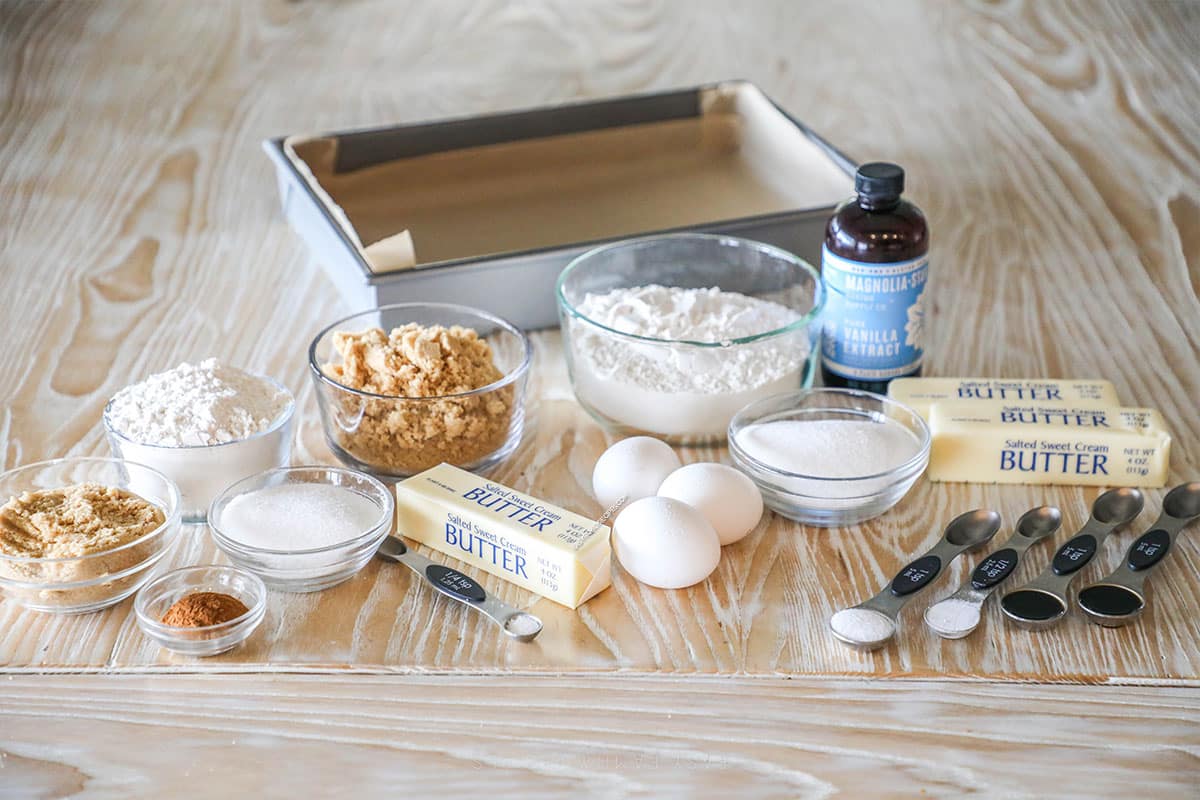 Ingredients needed to make cinnamon streusel blondies on a wooden background.