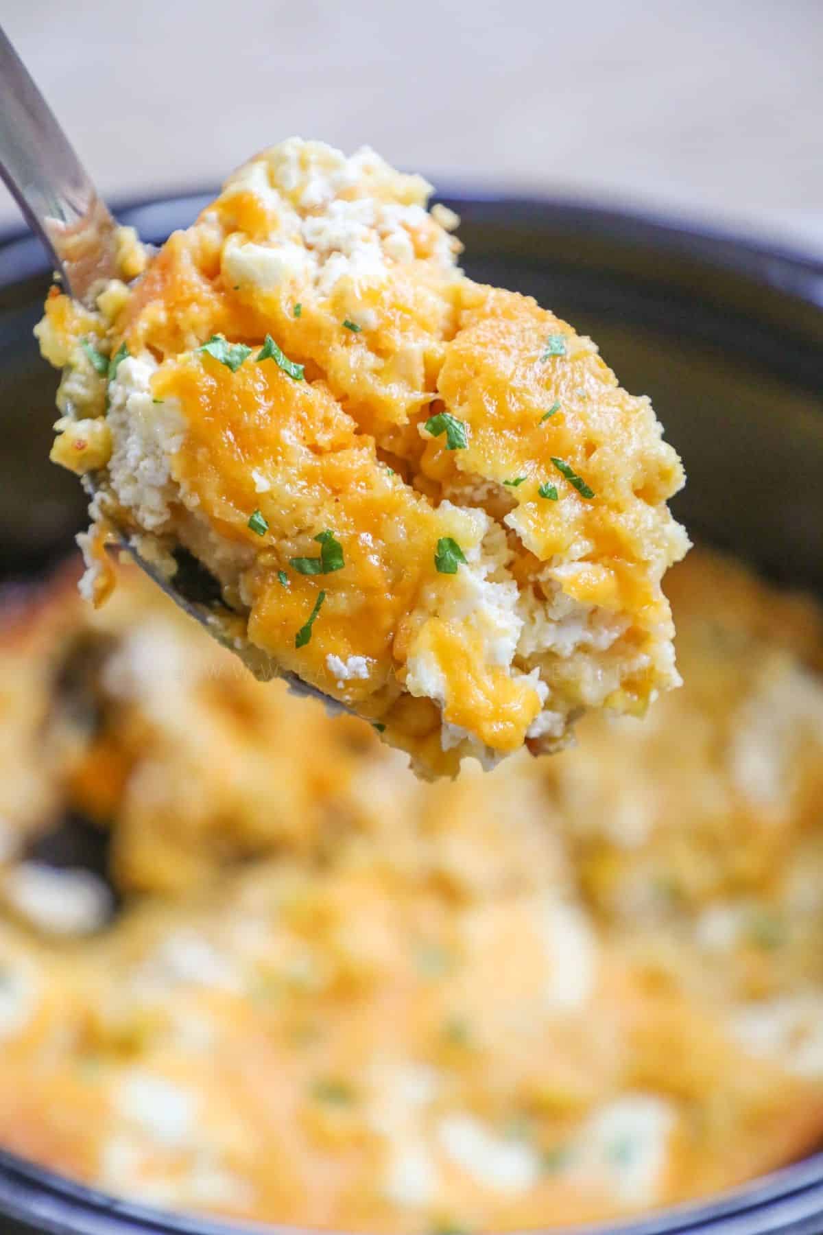 a scoop of corn casserole being lifted from a crockpot