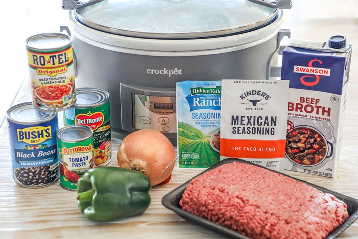 Ingredients for Crockpot Taco Soup including ground beef, green bell pepper, onion, tomato paste, Rotel, black beans, ranch seasoning, taco seasoning and beef broth.