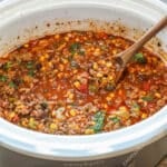 Easy crockpot taco soup in white crock pot with wooden spoon