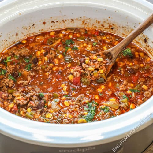 Easy crockpot taco soup in white crock pot with wooden spoon