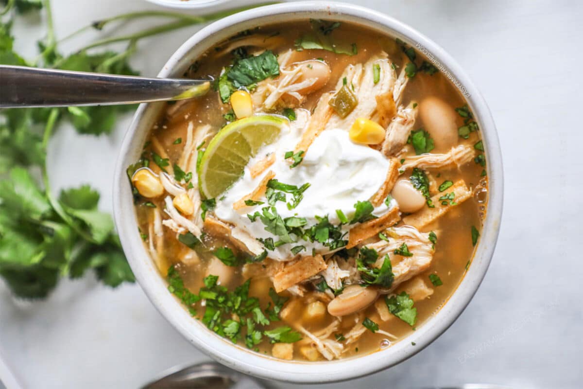 Southwest Chicken Chili Soup in a bowl with a scoop of sour cream and a lime wedge