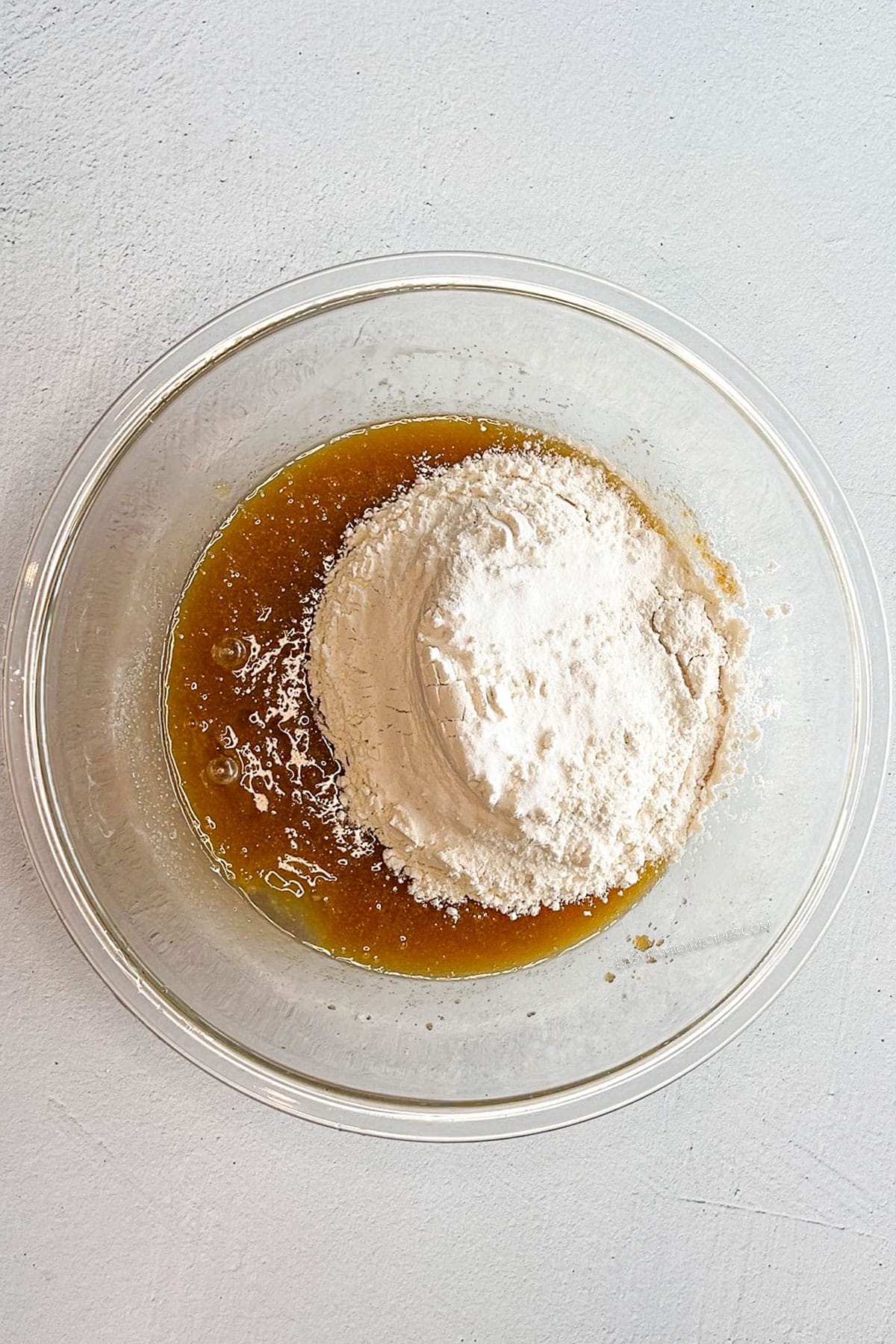 Flour, baking soda and salt added to the wet ingredients in a bowl.