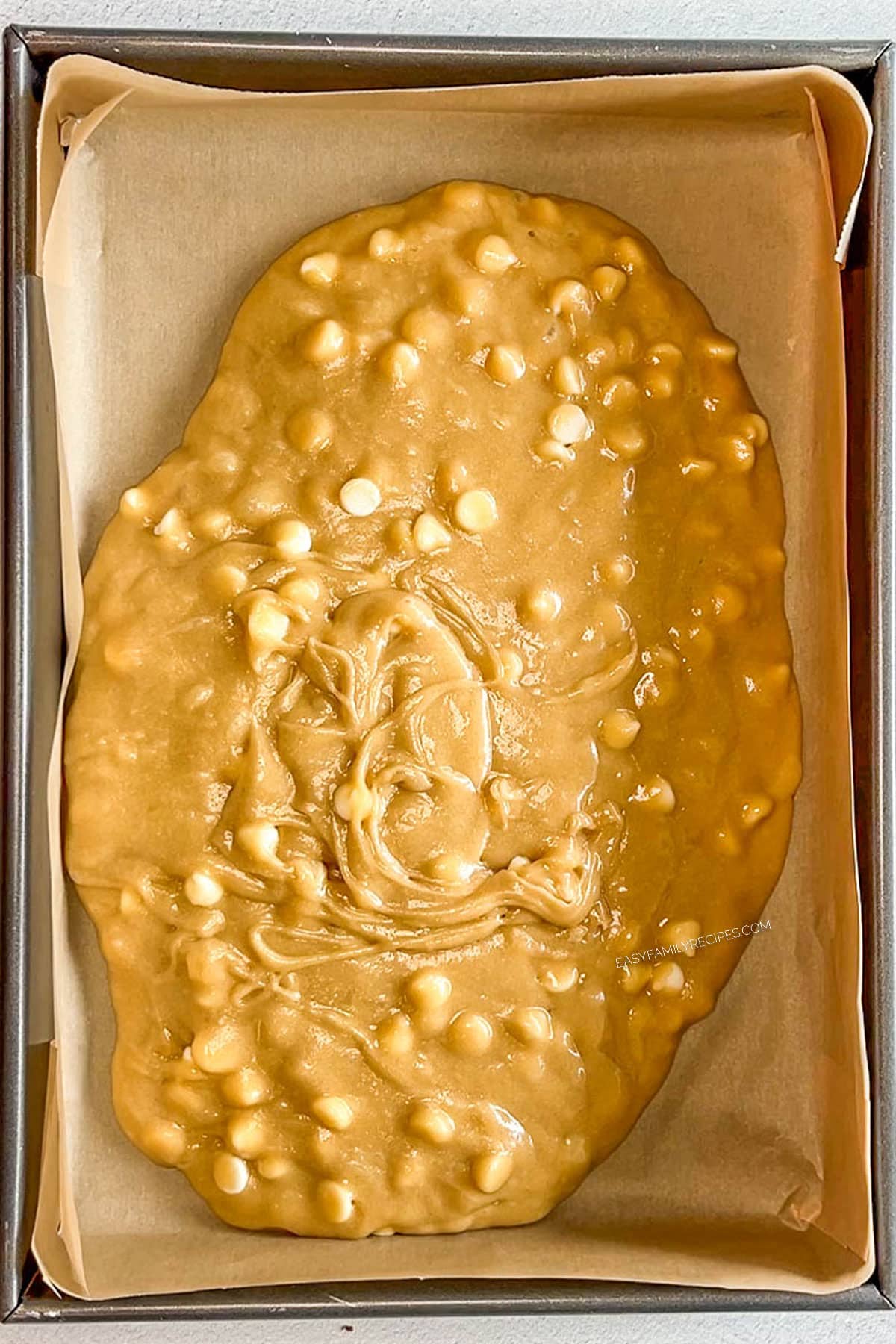 Blondie batter poured into a baking dish lined with parchment paper.