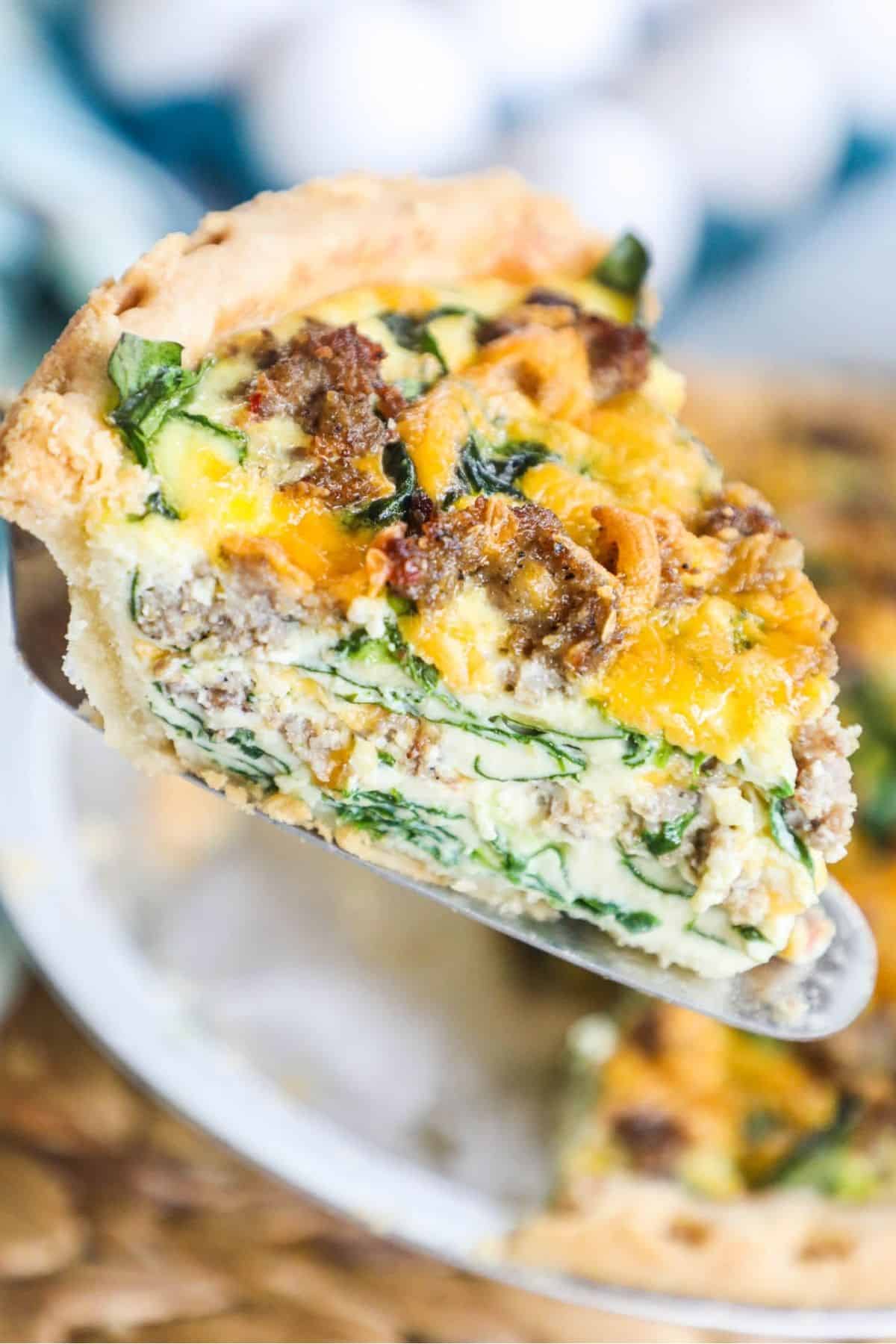 a slice of sausage and spinach quiche on a spatula