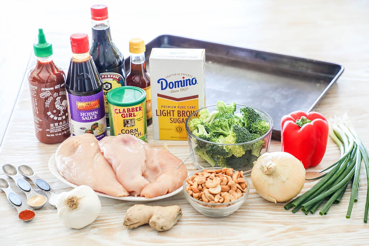 Ingredients needed to make sheet pan cashew chicken on a wooden background.