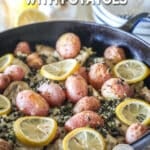 Skillet of baked lemon chicken thighs with potatoes with lemon slices on top.