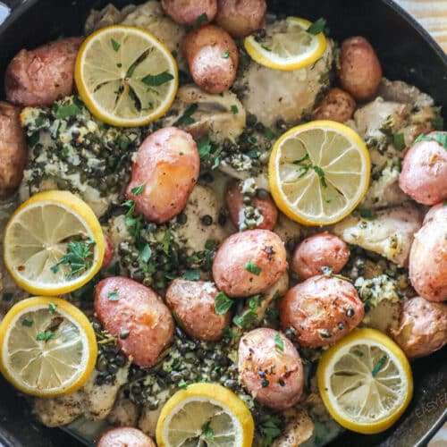 Overhead shot of baked lemon chicken thighs with potatoes in a cast iron skillet.