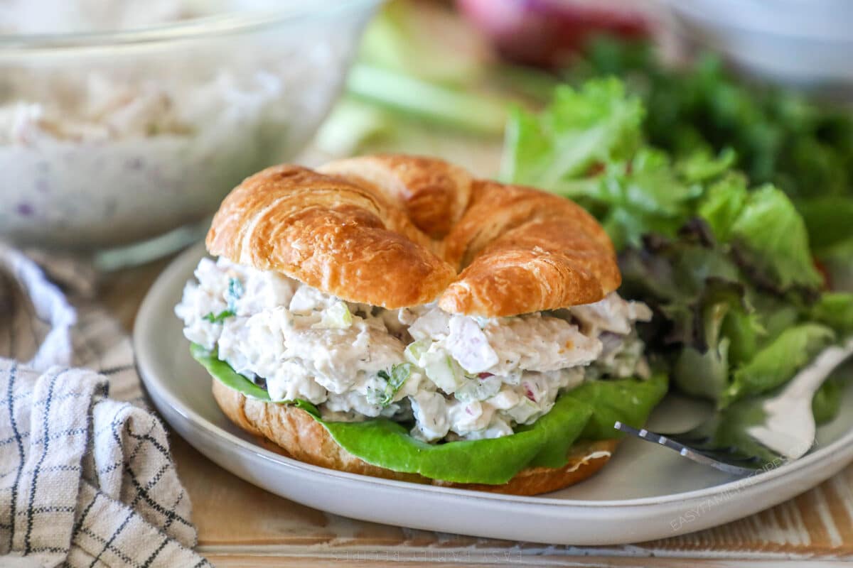a croissant turkey salad sandwich on a plate.