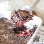 a scoop of black forest dump cake being scooped out of a baking dish.