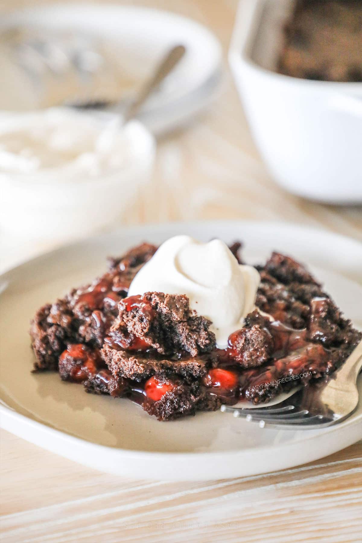 black forest cherry cake on a plate topped with whipped cream.