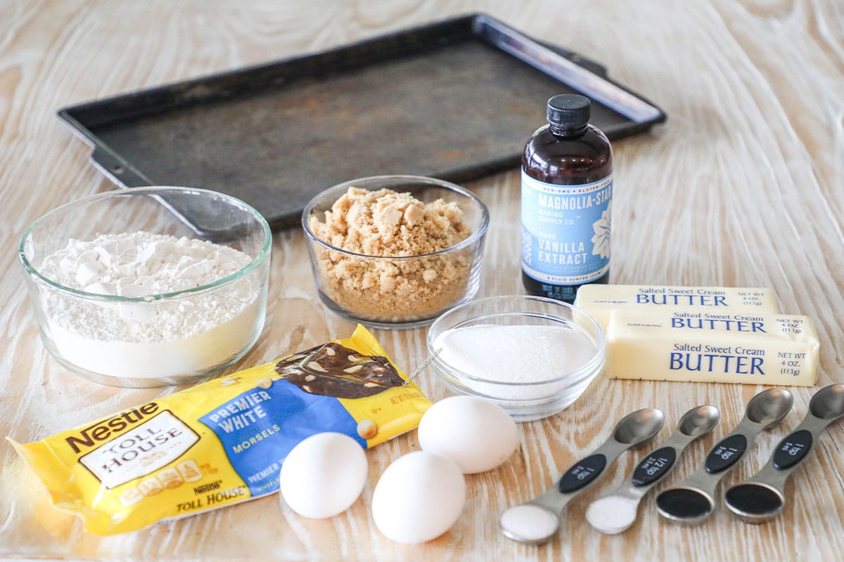 baking pan and ingredients to make brown butter blondies- including white chocolate chips, 3 eggs, butter, vanilla, brown sugar, sugar, flour and measuring spoons