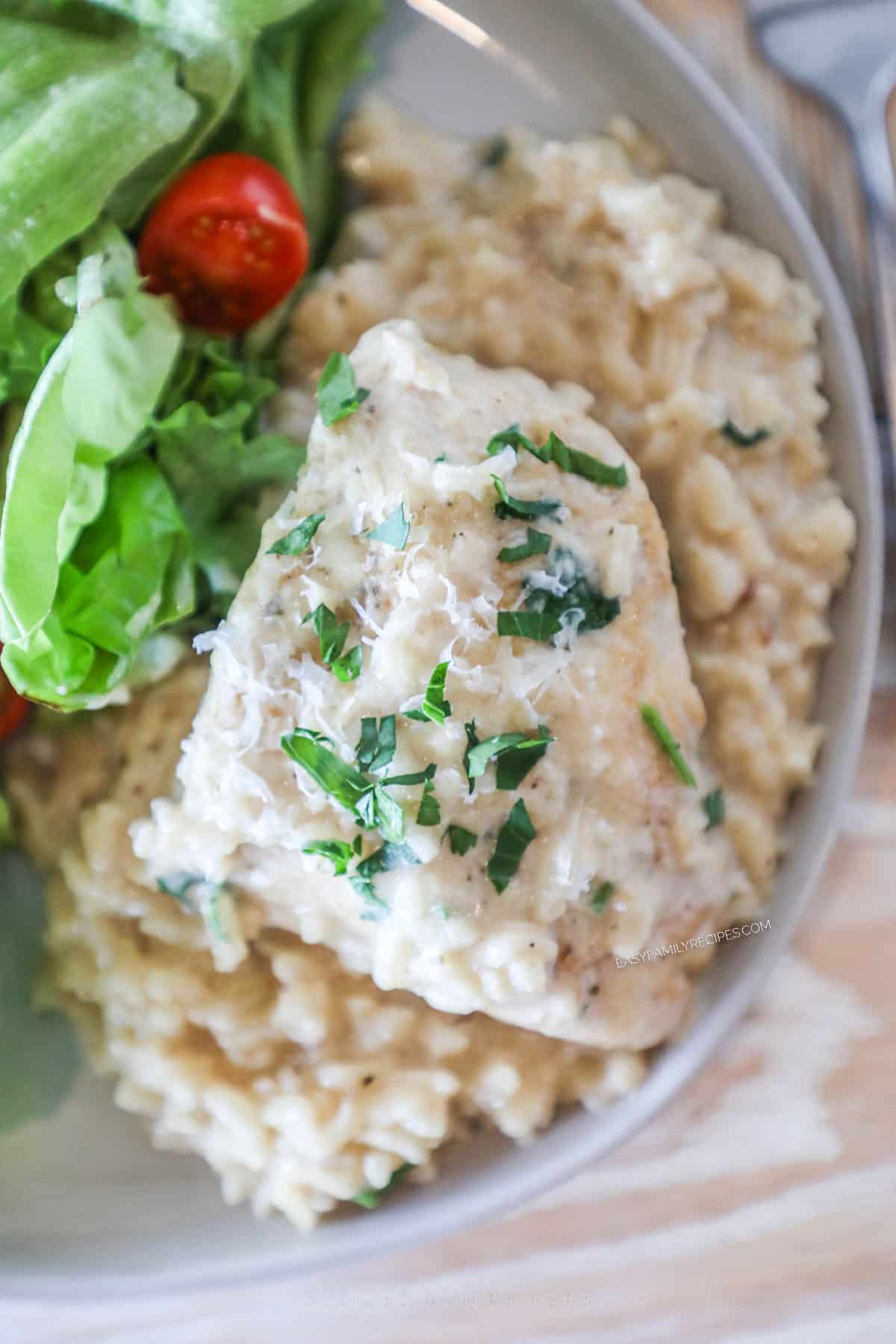 Overhead shot of a chicken thigh on top of creamy Boursin risotto on a plate.