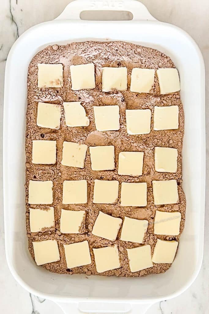 pats of butter layered on top of cake mix.
