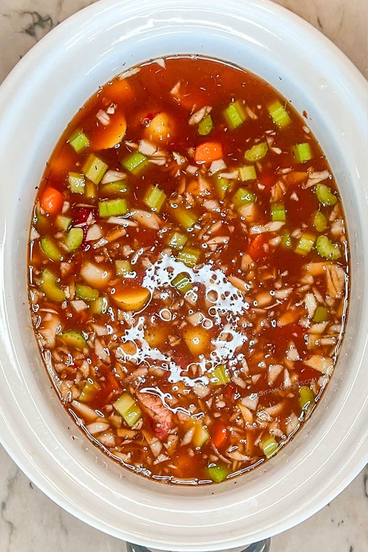 slow cooker beef stew ingredients in crock pot with beef broth poured over