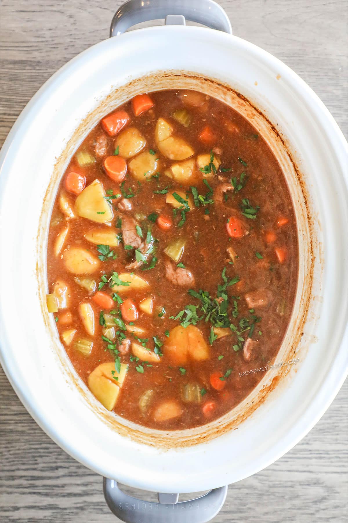 slow cooker beef stew in white crockpot after it has completed cooking
