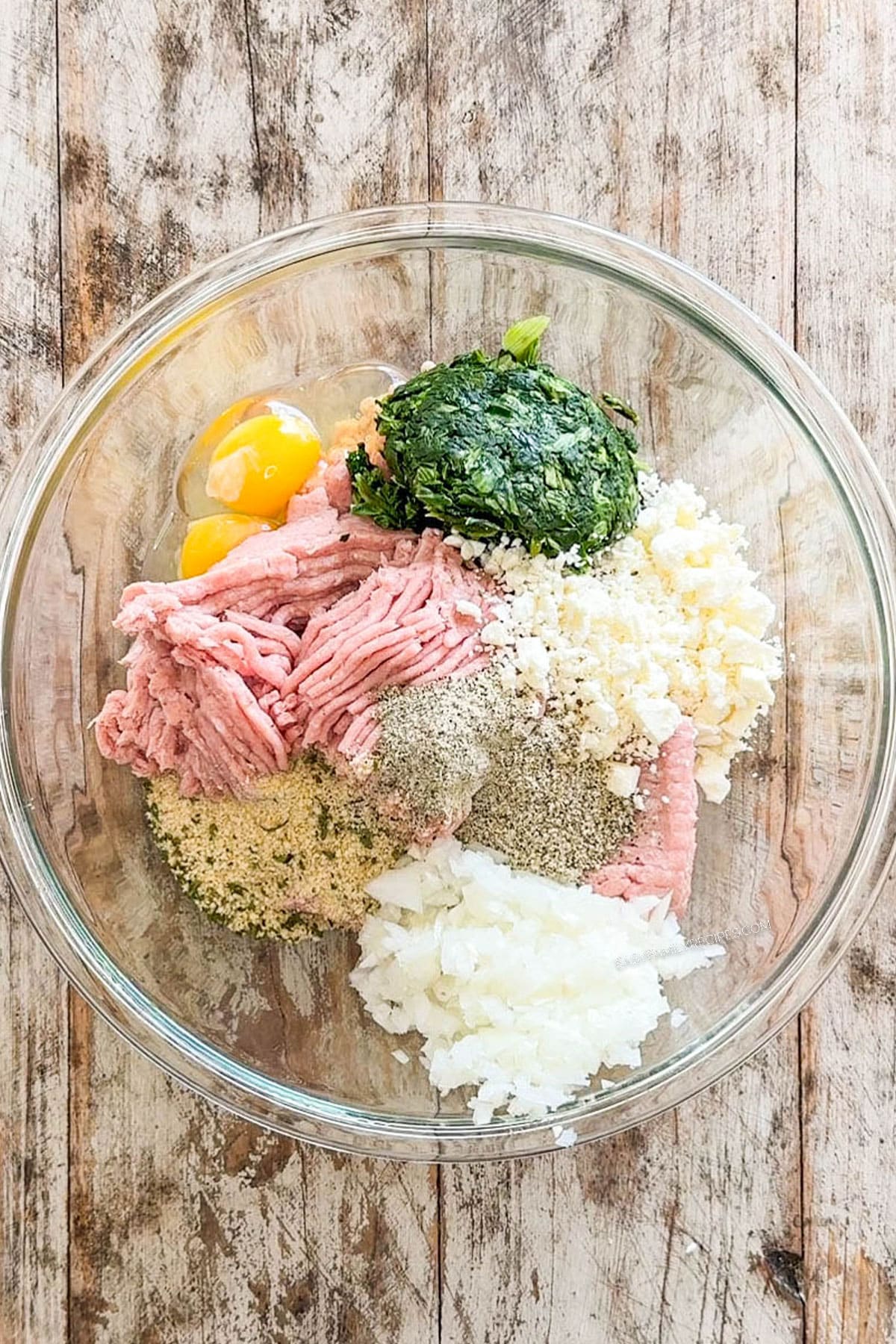 Ingredients for spinach feta turkey meatballs in a mixing bowl before being combined.