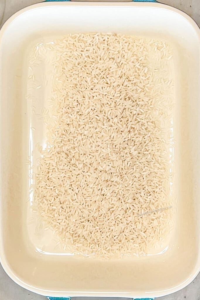 dry rice added to a baking dish.