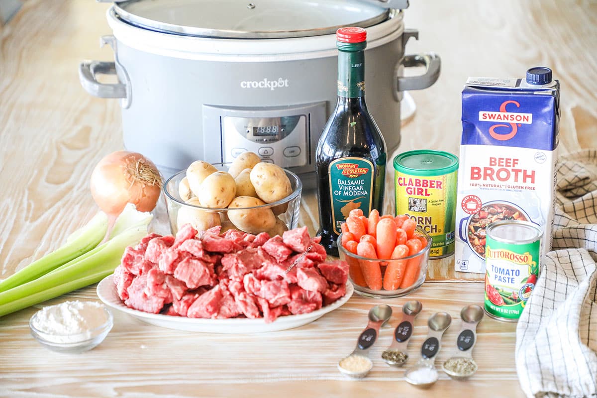 image of the ingredients needed for slow cooker beef stew, in front of a grey crockpot