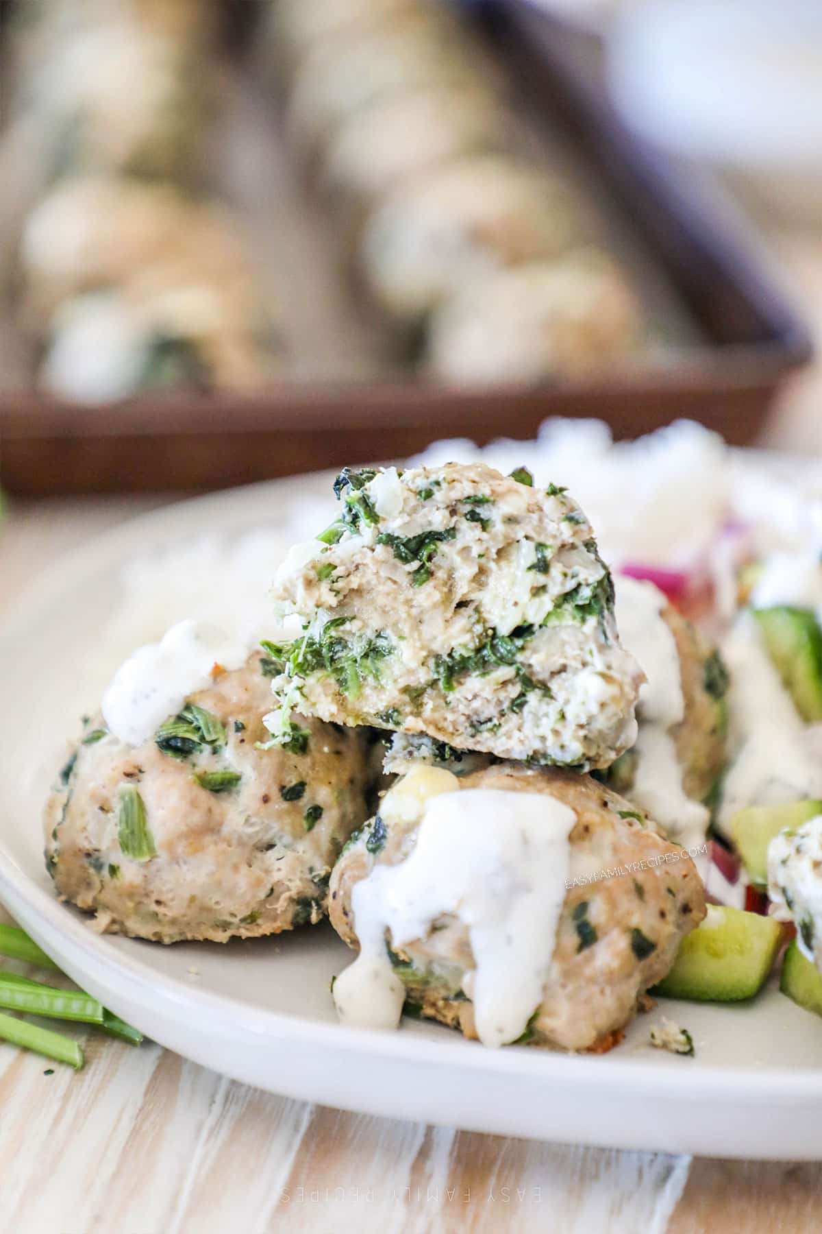 Spinach feta turkey meatballs on a plate with one broken in half to see the inside.
