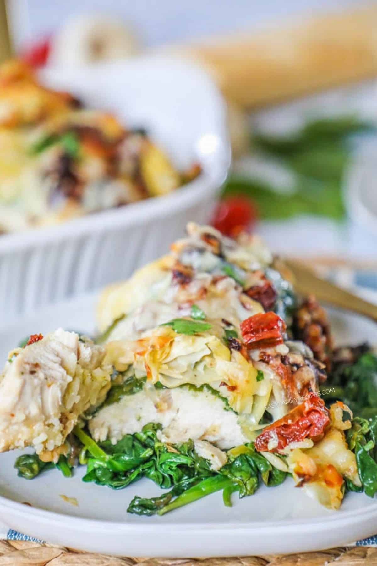 tuscan garlic chicken over a bed of spinach on a white plate