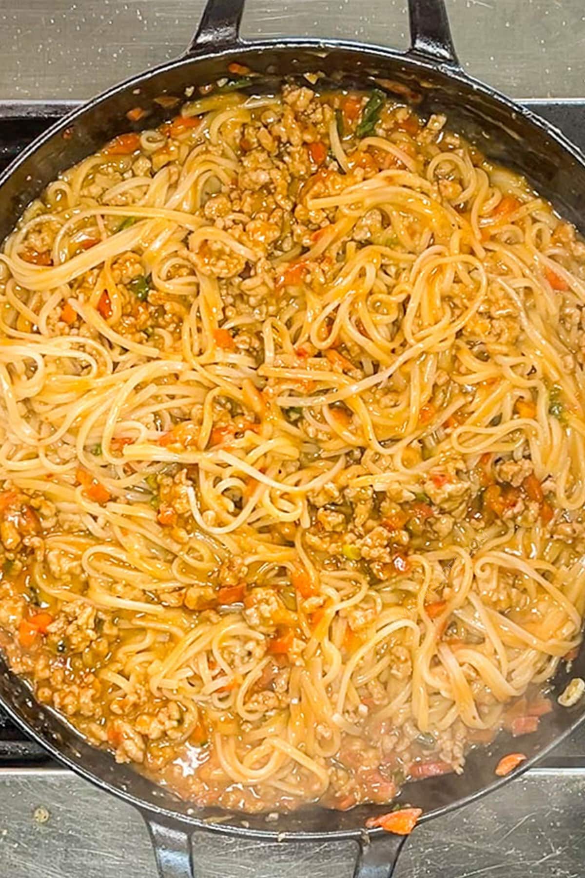 Noodles added to the sauce and ground pork in a large skillet.