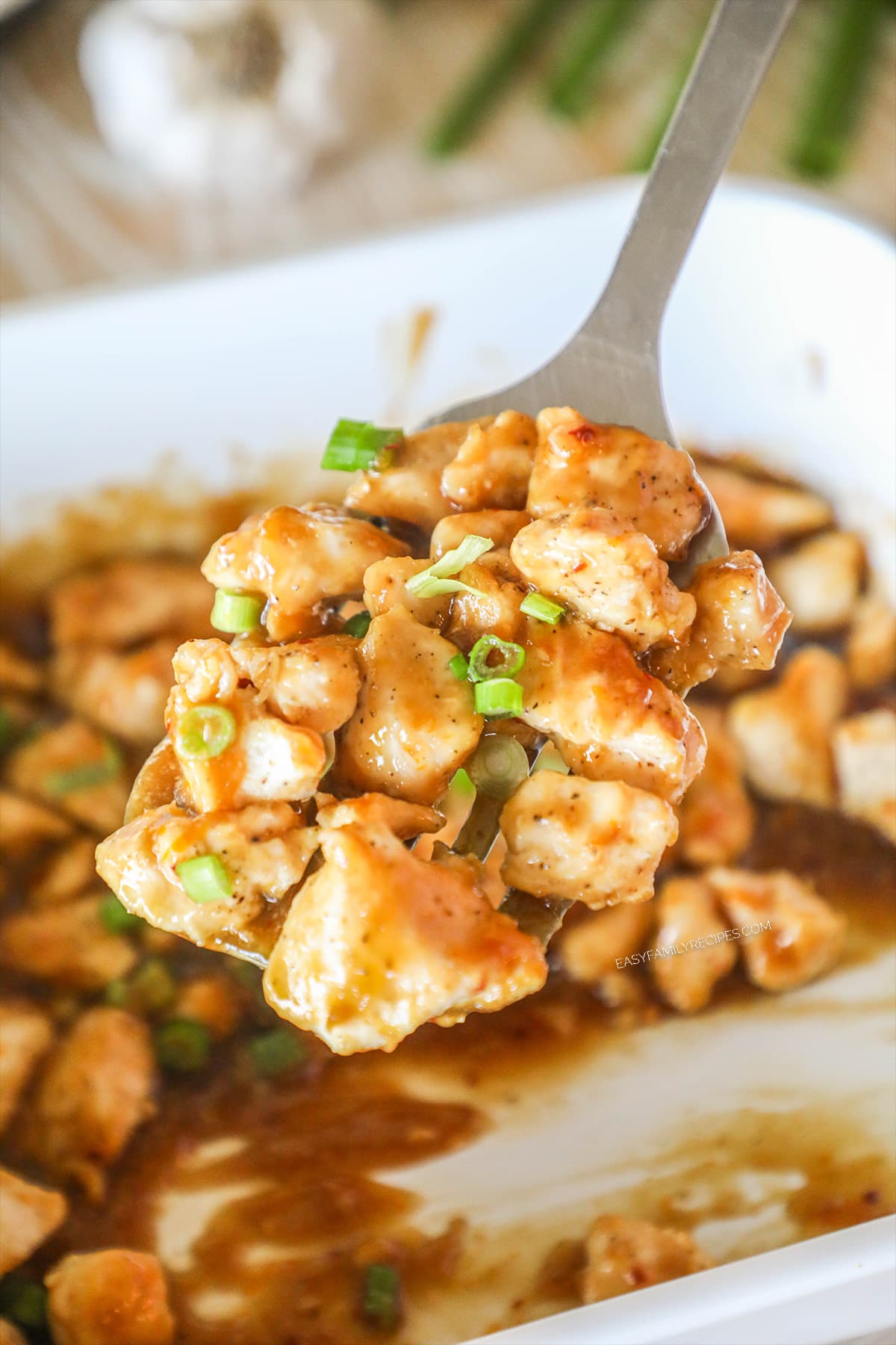 Oven baked orange chicken scooped up on a metal spatula.
